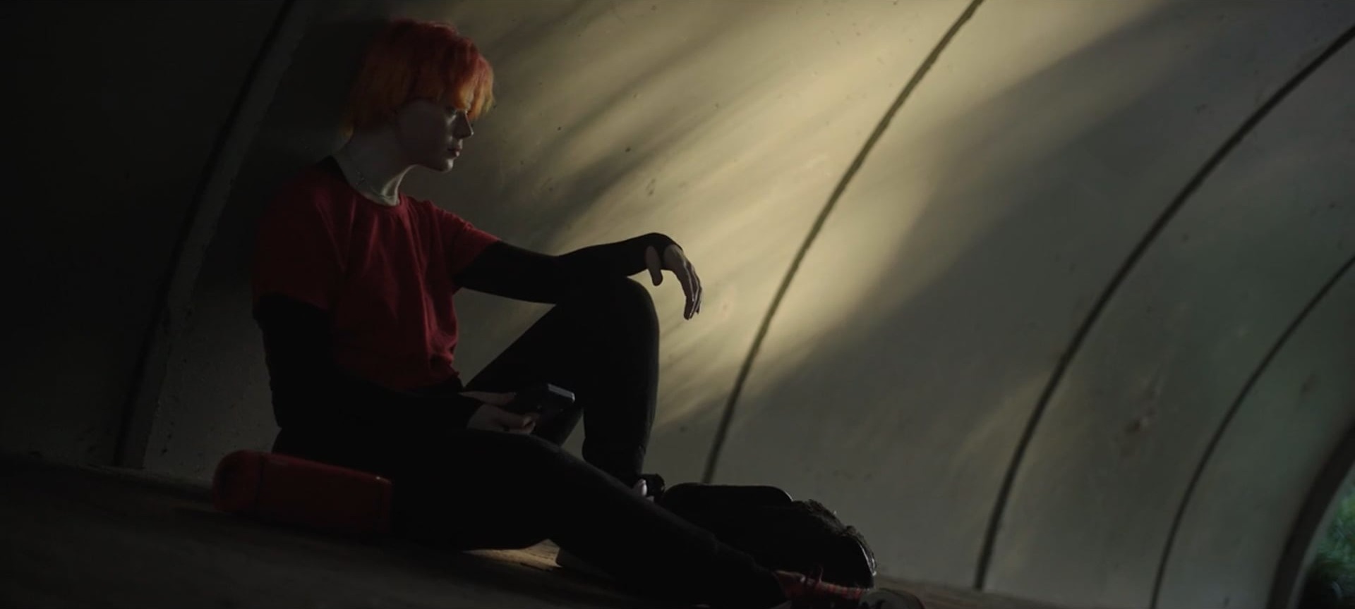 A figure in red sitting in a sunlit concrete tunnel, a still from Matthew's showreel